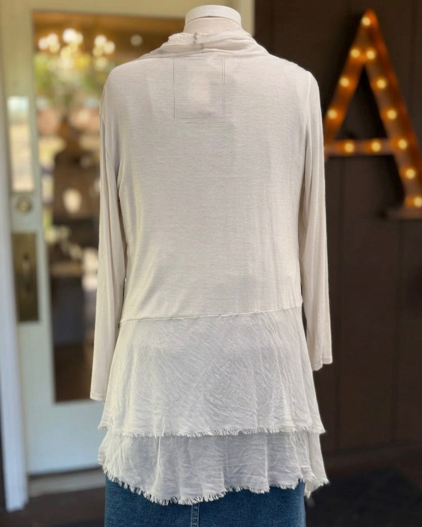 Back view of the Clara beige silk cardigan on a mannequin, showing long sleeves and a tiered, fringed hem.