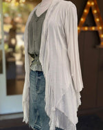 Angled view of the Clara beige silk cardigan, showing its long sleeve, cascading front panels and fringed edges.
