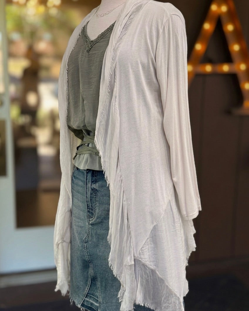 Angled view of the Clara beige silk cardigan, showing its long sleeve, cascading front panels and fringed edges.