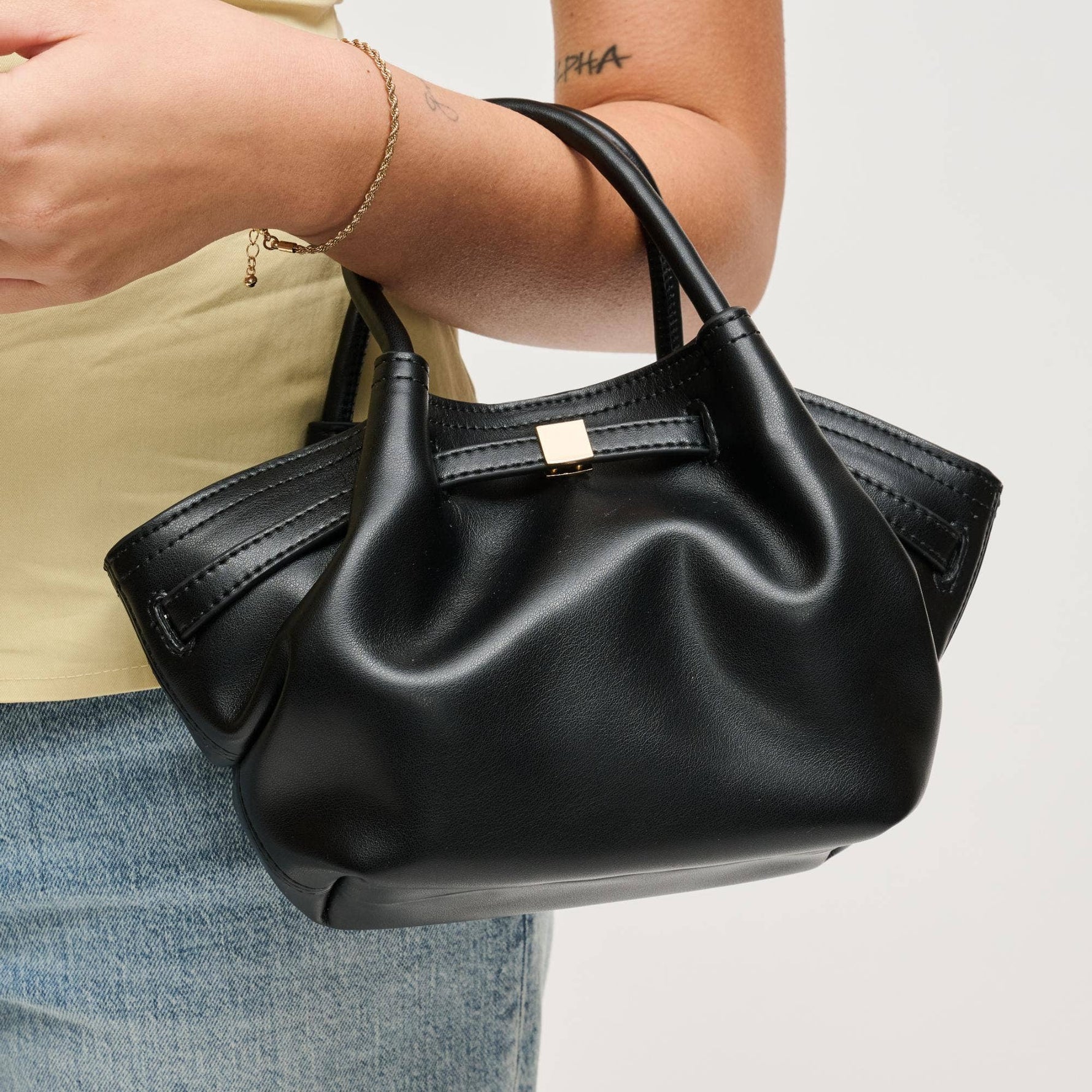 Close-up of the Selena Crossbody in black vegan leather featuring a softly gathered silhouette, rolled top handles, and gold-tone hardware.