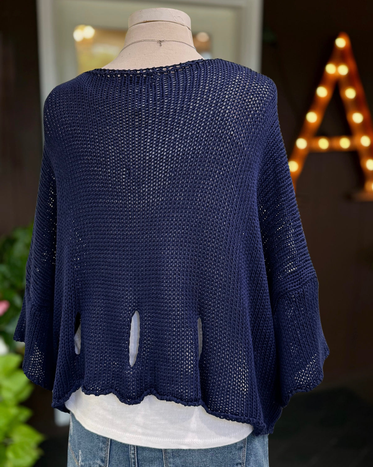 Back view of the Eleni navy cropped sweater, showing open-knit texture and teardrop cutouts near the hem.