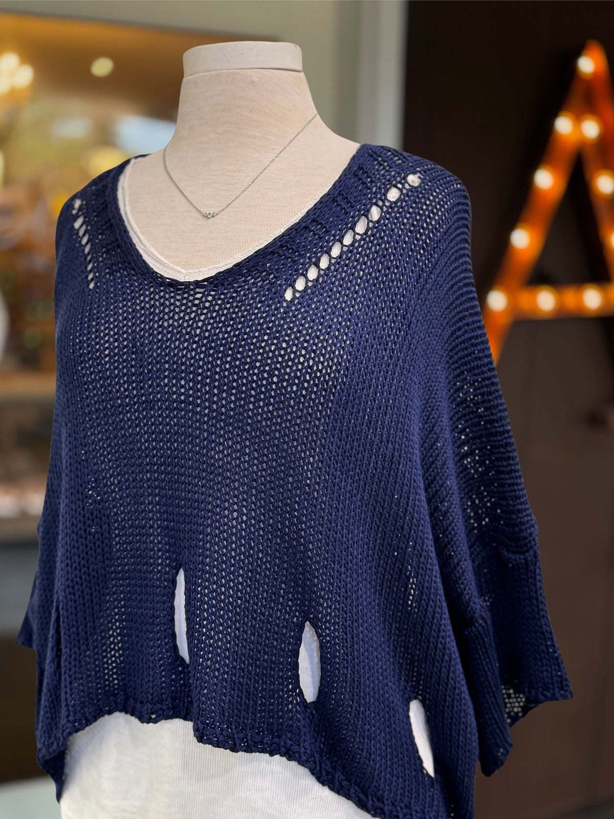 Eleni navy cropped sweater on a mannequin, showing open-knit texture and cutouts at the shoulders and hem.