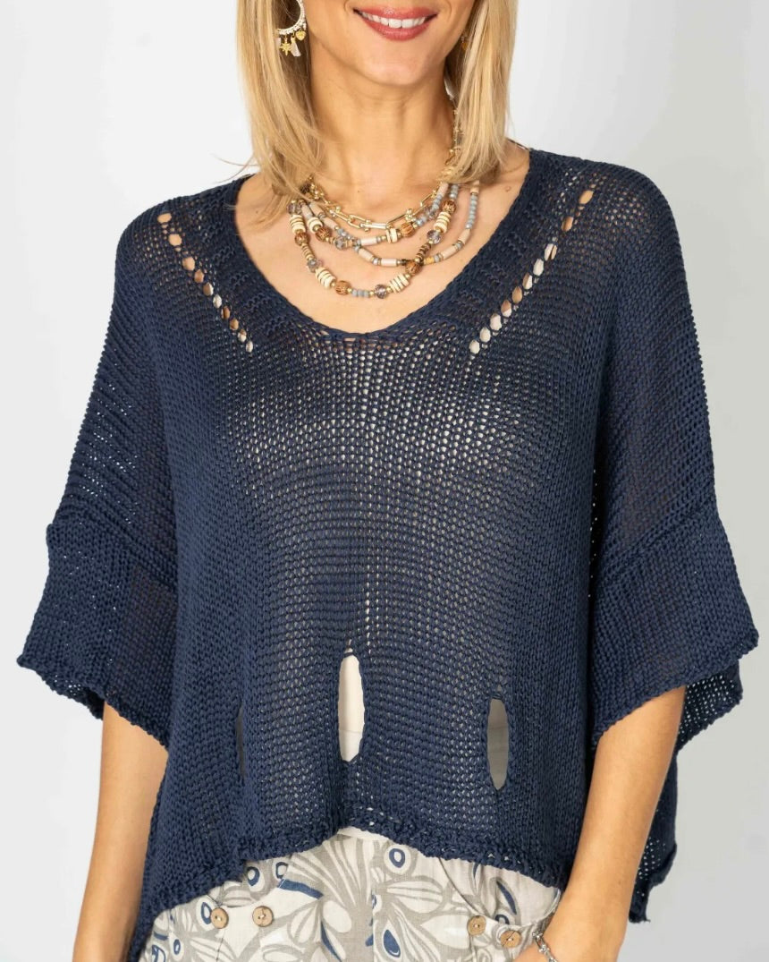 Model wearing the Eleni navy cropped sweater with layered necklaces and patterned bottoms, showing its open knit.