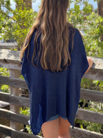 Back view of the Elise Wrap Poncho in Navy on a model, showing its textured knit and draped hem.