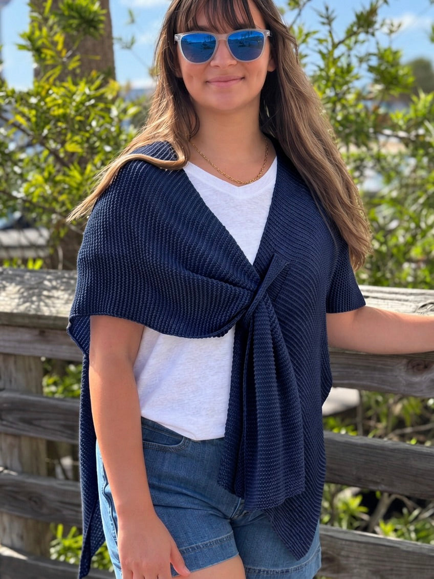 Elise Wrap Poncho in Navy tied at the front over a white top and denim shorts on a model outdoors.