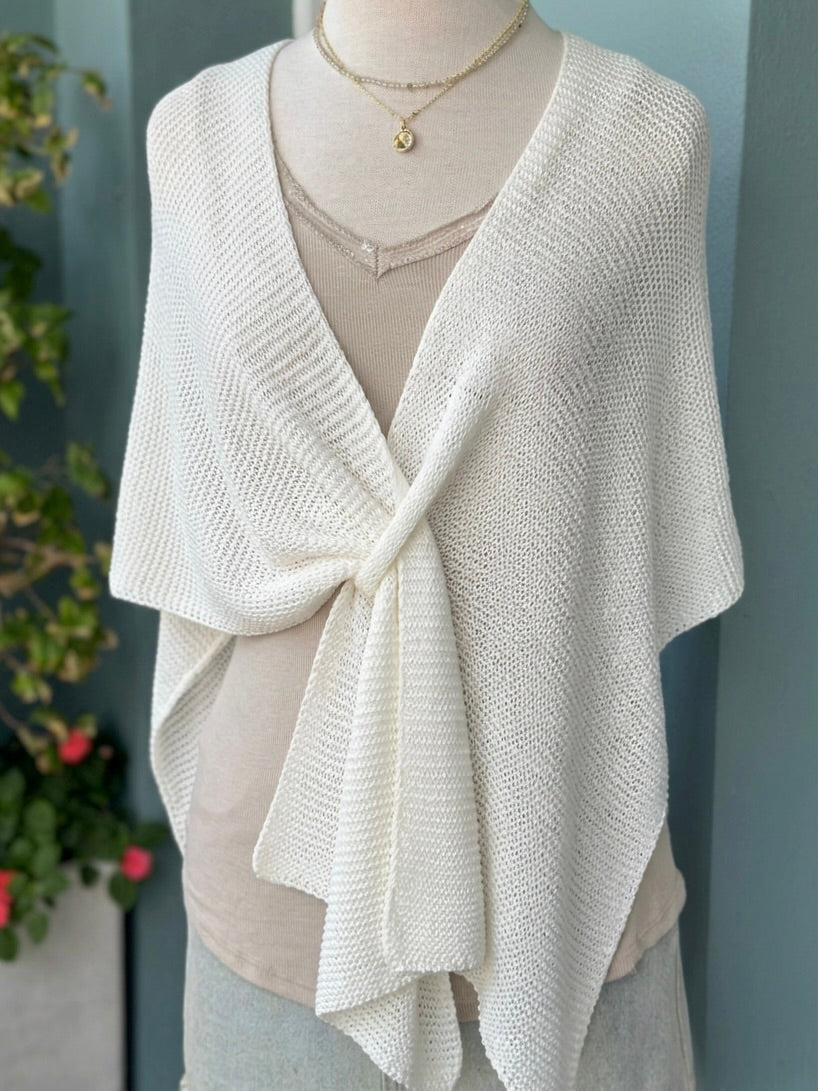 Elise Wrap Poncho in White tied at the front on a mannequin over a beige top, styled with layered necklaces.