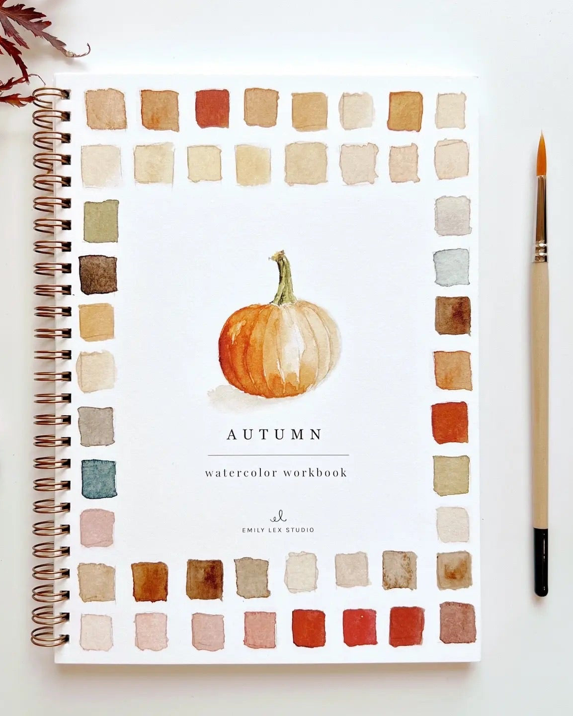 Autumn Watercolor Workbook by Emily Lex Studio featuring a watercolor pumpkin and fall color palette, surrounded by warm autumn hues and art tools.