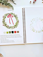 Christmas Watercolor Workbook open to wreath painting page with step-by-step instructions, color palette, and outline sketch by Emily Lex