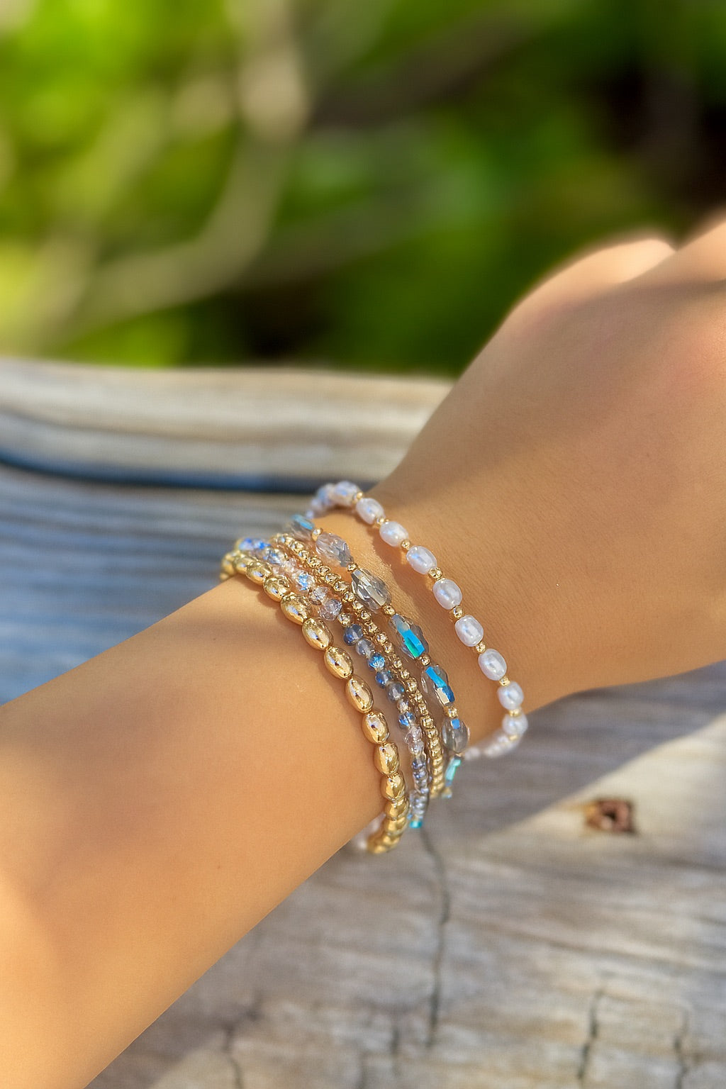 Stack of bracelets on a wrist with a blurred natural background