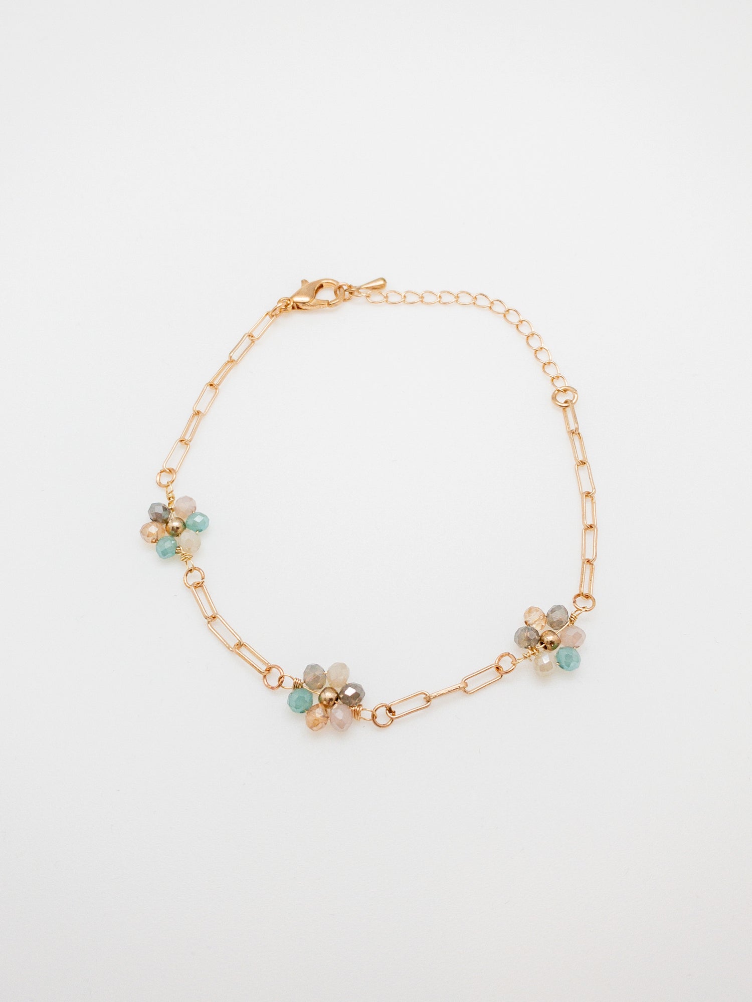 A gold-plated bracelet with multicolored daisy-shaped clusters on a white background.