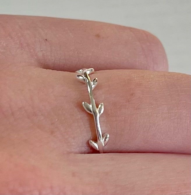 A sterling silver ring with a simple design, featuring two leaf-like embellishments on the band.