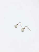 A pair of ivory-colored earrings with a spherical design, displayed against a white background.