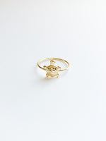 A gold-colored turtle-shaped ring against a white background.